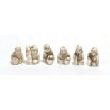 A set of six Japanese ivory netsukes, Meiji period, each as a seated figure holding various items,