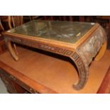 A 20th century Chinese carved hardwood coffee table with glass top