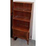 A reproduction inlaid mahogany three-tier waterfall bookcase, fitted with a base cupboard and moving