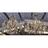 A pair of sixteen light gilt brass lustre drop chandeliers, with scroll and leaf cast arms