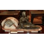 An Art Deco pink marble striking mantle clock with figure of a seated lady