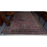 A Herati rug, the raspberry field with floral motifs, within confirming borders,
