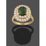 A Green Zircon and Diamond Cluster Ring, the oval green zircon in a yellow four claw setting, within