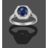 A Sapphire and Diamond Cluster Ring, the round cut sapphire in a white four claw setting within a