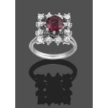A Garnet and Diamond Cluster Ring, the round cut oval garnet within a border of round brilliant cut