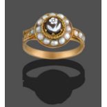 An Onyx and Seed Pearl Mourning Ring, the onyx carved to depict a forget-me-not in a yellow claw and