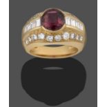 A Garnet and Diamond Ring, the oval cut garnet sits between graduated baguette cut diamonds, in