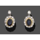 A Pair of Sapphire and Diamond Drop Earrings, the oval cut sapphire in a yellow rubbed over setting,