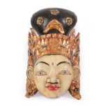 A South East Asian Carved, Painted and Gilt Mask, with extensive leaf and scroll carved headdress