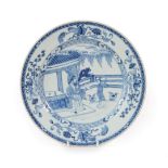 A Chinese Porcelain Dish, Kangxi, painted in underglaze blue with figures in a fenced garden
