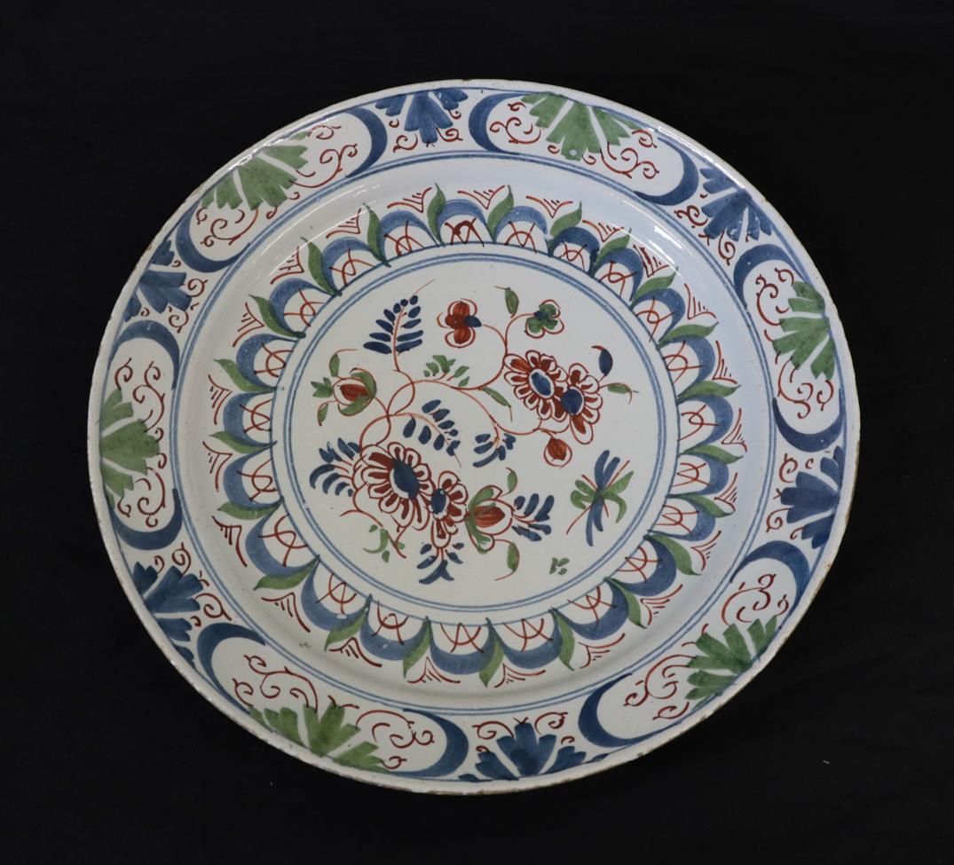 An English Delft Plate, mid 18th century, painted in colours with a central flowerspray within