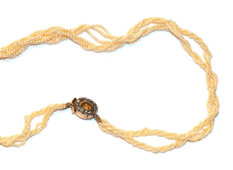 A seed pearl necklace with a browny-orange stone and diamond set clasp, length 40.5cm. Clasp stamped