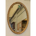 An early 20th century gilt and gesso oval mirror, the frame decorated with husks