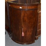 A George III mahogany bow fronted hanging corner cupboard