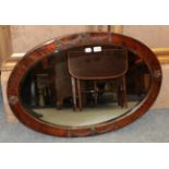 An oval copper framed mirror decorated with rams heads and swags, together with an oval mahogany