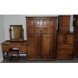 A reproduction oak five piece linen fold bedroom suite comprising: wardrobe, bedside chest, dressing