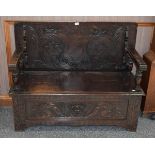 A 19th century carved oak monks' bench, with hinged seat and carved front panel