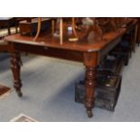 A Victorian mahogany extending dining table on turned legs, with brass capped castors