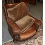 An early 20th century brown leather armchair, with carved arm supports