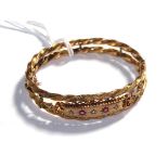 A ruby and diamond hinged bangle, stamped '9CT'. Gross weight 11.17 grams