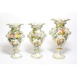 A Continental porcelain vase garnitures, each painted with vignettes of pastoral scenes, tallest