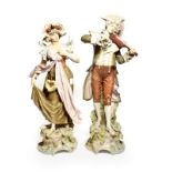 A pair of post 1919 Royal Dux figures of a musician and maiden in floral shawl and bonnet, model