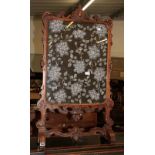 A Victorian carved walnut fire screen with floral bead work panel