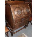 An early 20th century carved oak bureau with moulded panel front