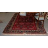 A Yagibedir carpet, the claret angular latch hook lattice field enclosed by indigo borders, 277cm by