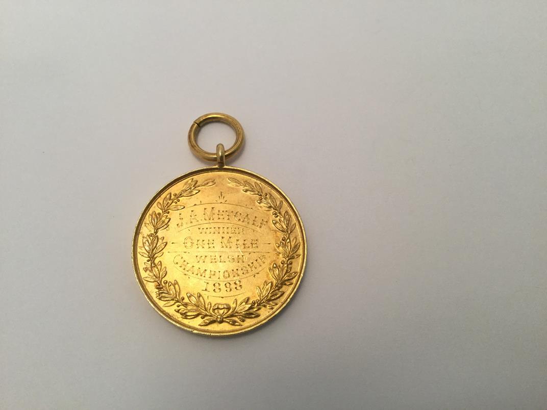 A Victorian Gold Medal, Stamped '15ct', Dated 1897, circular the obverse with a shield chased with - Image 3 of 3