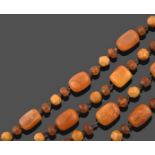 An Amber Bead Necklace, formed of yellowy-orange smooth barrel shaped amber beads spaced by trios of