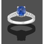 A Sapphire and Diamond Ring, the oval cut sapphire in a white claw setting to round brilliant cut