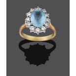 An 18 Carat Gold Aquamarine and Diamond Cluster Ring, the oval cut aquamarine within a border of