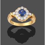 A Sapphire and Diamond Cluster Ring, the round cut sapphire in a yellow claw setting, within a