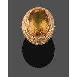 A Citrine Ring, the oval cut citrine in a yellow rubbed over setting, within a ropetwist border,