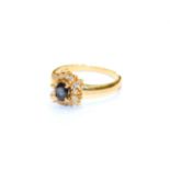 An 18 carat gold sapphire and diamond cluster ring, the oval cut sapphire within a border of round