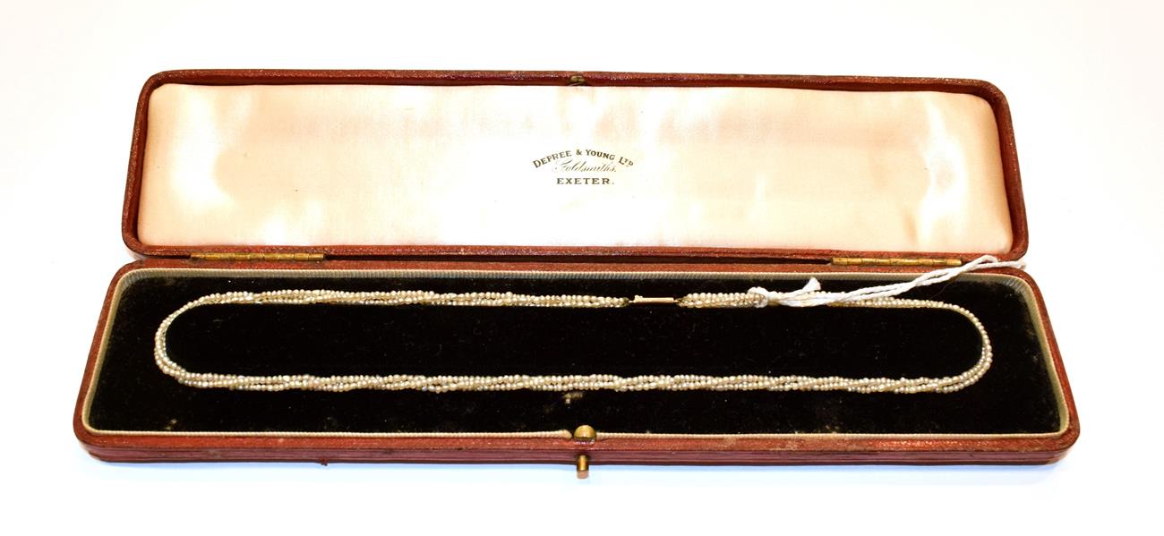 A seed pearl necklace, circa 1900, three rows of strung seed pearls knotted to a clasp stamped '