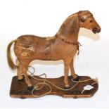 A late Victorian leather toy pull along horse, raised upon a wooden base with wheels, 32.5cm 33cm
