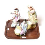 A Meissen figure of a man seated flanked by two baskets, together with two other continental figures