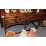 A reproduction oak dresser base with four geometric moulded drawers