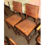 A pair of oak chairs with studded and embossed leather work decorated with leaves and scrolls