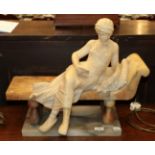 A late 19th/early 20th century alabaster figure of a lady reclining on a bench, 45.5cm high by