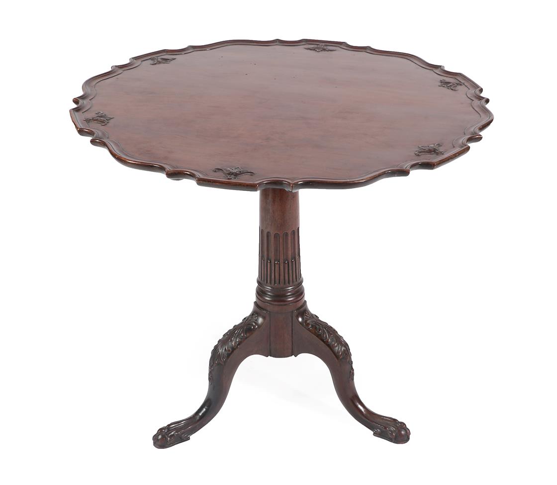 A George III Style Carved Mahogany Tripod Table, the scalloped top above a block support and stop-