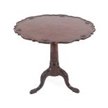 A George III Style Carved Mahogany Tripod Table, the scalloped top above a block support and stop-