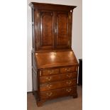 An 18th Century Oak Bureau Bookcase, the moulded cornice above twin panelled doors, shelved
