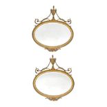 A Pair of Adam Style Gilt and Gesso Oval Mirrors, the moulded and beaded frames surmounted by