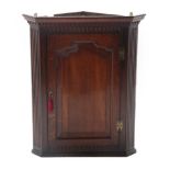 A George III Oak Hanging Corner Cupboard, 3rd quarter 18th century, the dentil and fluted cornice
