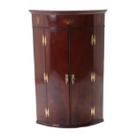 A George III Mahogany Bowfront Hanging Corner Cupboard, late 18th century, with oval patera