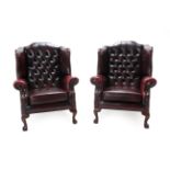 A Pair of Wing-Back Armchairs, modern, upholstered in red close-nailed leather, with buttoned back