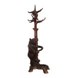 A Late 19th Century Black Forest Carved Bear Hall Stand, with a bear beside a tree holding a branch,